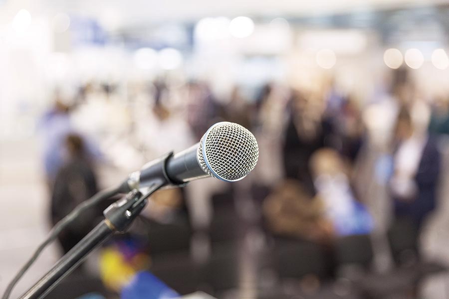 Microphone in the foreground in front of a blurred audience